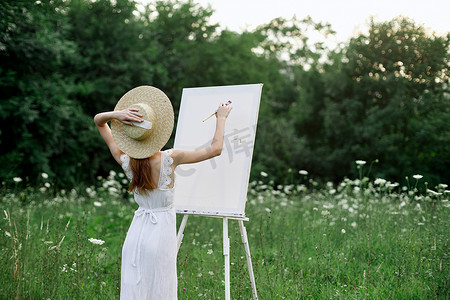 学生画画摄影照片_一位穿着白色裙子的女人在鲜花田里画了一幅画