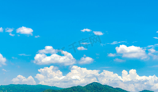 蓝蓝的天空和白色的积云在绿色的山上。