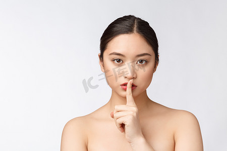 白色背景中，亚洲女性用手指放在嘴唇上做出安静手势的肖像