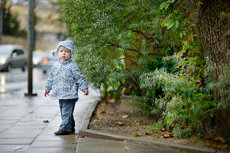 秋天雨天摄影照片_可爱的蹒跚学步的女孩在雨天