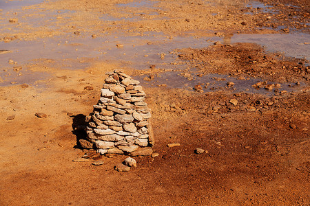 湿垃圾摄影照片_泥泞的地面充满了泉水，一侧有一堆石头。
