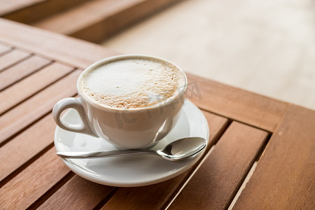 咖啡店咖啡馆桌子上的陶瓷杯咖啡。木桌上咖啡馆的咖啡杯拿铁艺术。经典咖啡杯，意大利卡布奇诺，美味的早晨热饮。