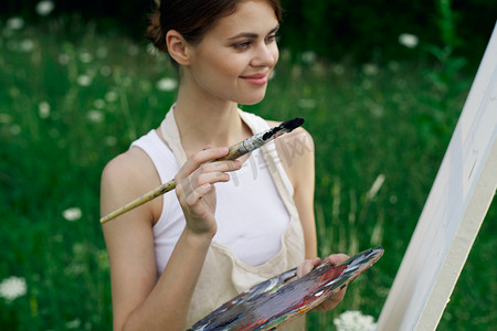 穿着白色连衣裙的女人，在自然艺术画上涂着调色板
