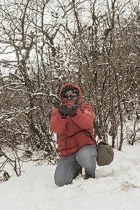 夏天雪山摄影照片_一个穿着红色套头夹克的女人微笑着快乐地享受着第一场雪的玩耍和向空中扔雪球的肖像。