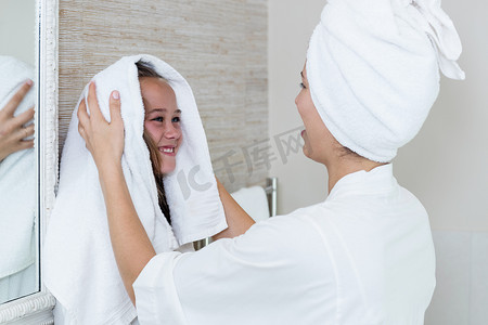 擦头发摄影照片_母亲用毛巾擦干女儿的头发