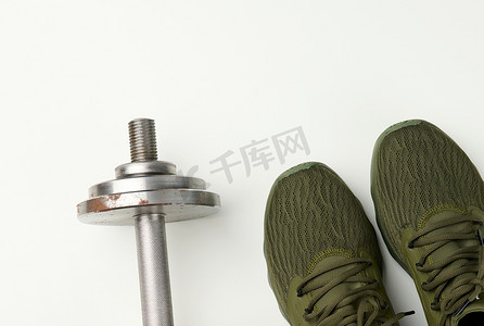 一双绿色纺织运动鞋和一个白色背景的金属哑铃，顶视图。