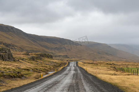 在多雨的灰色天气中沿着冰岛海岸的冰岛砾石路的公路旅行