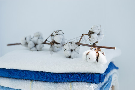 一堆干净的浴巾彩色棉毛圈纺织品，一根棉枝折叠在木椅上，靠着白墙小睡概念特写