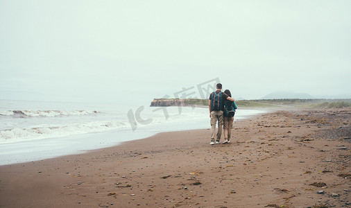 拥抱恩爱摄影照片_旅行者恩爱的情侣在海边的海滩上散步