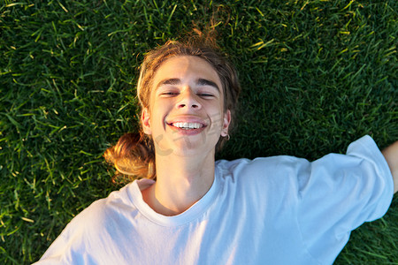 16、17 岁帅哥在绿草上的特写脸，顶视图