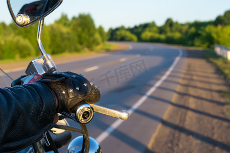 荆棘道路摄影照片_摩托车控制手柄上骑自行车的人的手的特写和道路的视野