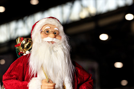 装饰玩具圣诞老人穿着红色皮大衣以夜城为背景。