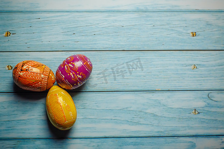 蓝色彩绘背景摄影照片_蓝色木质背景平躺上的复活节彩色彩绘鸡蛋