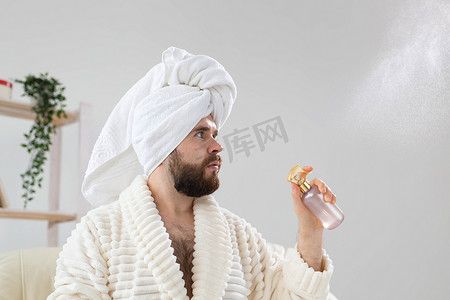 留着胡子的男性头上戴着浴巾，在脸上进行喷雾水处理。