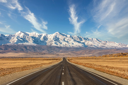 拍摄一条笔直空旷的高速公路，通往库雷山脉的雪峰。