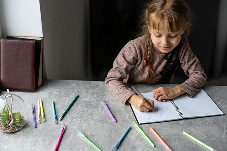 可爱的小女孩在家庭室内背景中做作业，特写