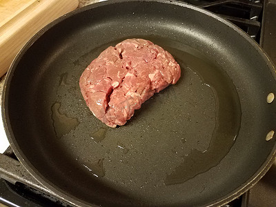 在炉子上的煎锅里加油的生牛排肉