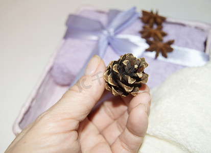 一位女士的手用金锥装饰圣诞礼物，包装毛巾，为节日做准备