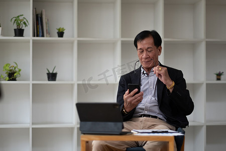 使用移动智能手机和木桌上数字平板电脑的亚洲老老人