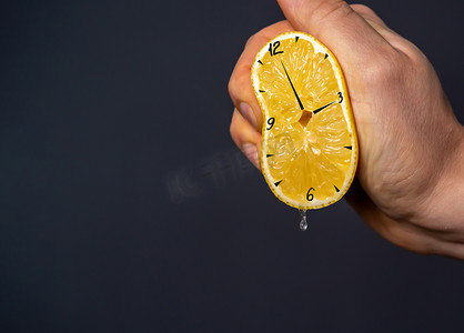 融合教育摄影照片_手挤出一个柠檬，上面画着时钟。