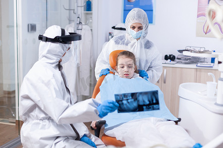 放射防护摄影照片_穿着个人防护服的小女孩和母亲看牙科射线照相