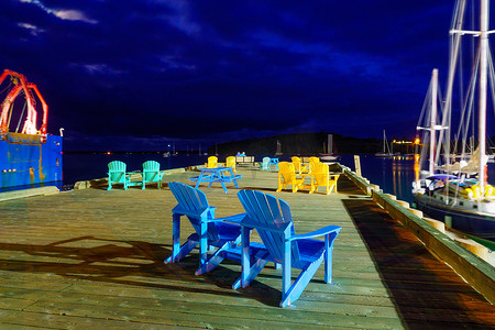 卢嫩堡港夜间带彩色椅子的码头