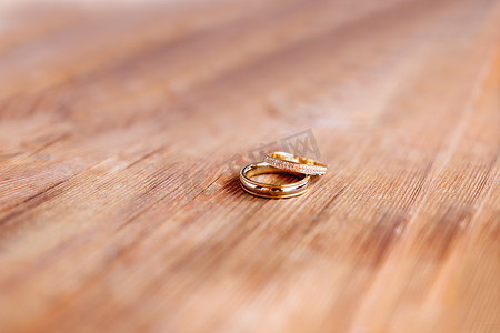 一对金色结婚戒指，在破旧的木制背景上镶有钻石。