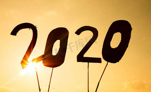 在夕阳的天空背景和阳光透过文字照耀下，回收纸板的剪影变成 2020 年的数字。