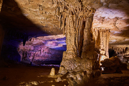 洞穴中的大型岩层，表面蜡质，背景中发出紫色光芒