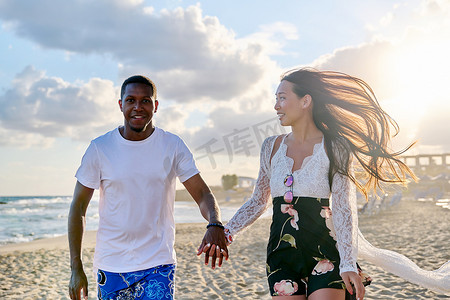 快乐的年轻夫妇一起沿着海滩跑步