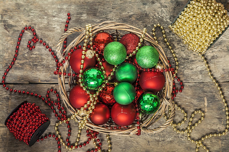 圣诞球红色摄影照片_圣诞球红色、金色、绿色、珠子放在木篮里