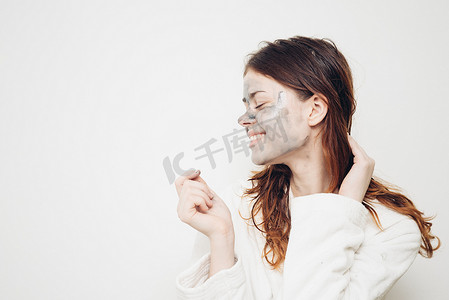 乳清摄影照片_穿浴袍、面霜、护肤品的快乐女人
