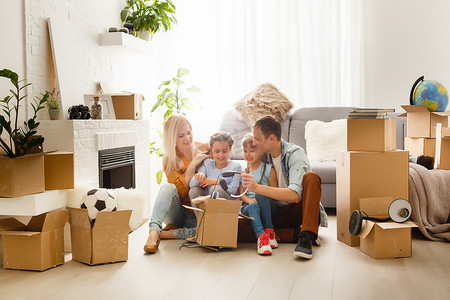搬家背景摄影照片_幸福的家庭在搬家那天在新房子里装着纸板箱。