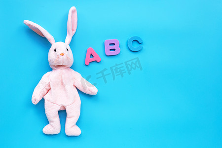 立方体的兔子摄影照片_蓝色背景上有英文字母表的兔子玩具。