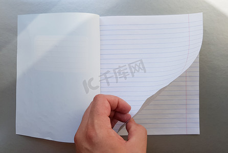 翻开杂志摄影照片_设计理念-高品质男性手翻阅一张蓝色条纹笔记本的顶视图。