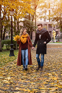 情侣牵着手摄影照片_热恋中的情侣牵着手漫步在金色的秋天公园。