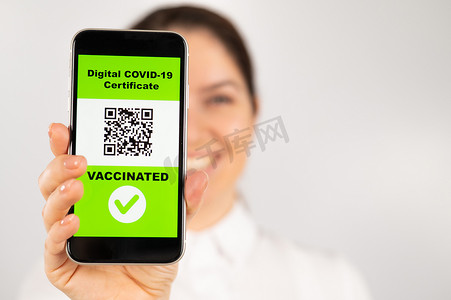 扫一扫关注二维码摄影照片_一位女士展示带有有关疫苗接种的二维码的智能手机。