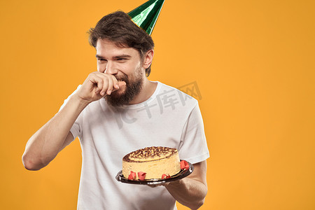 戴着帽子的生日男孩，带着蛋糕有趣的黄色背景派对