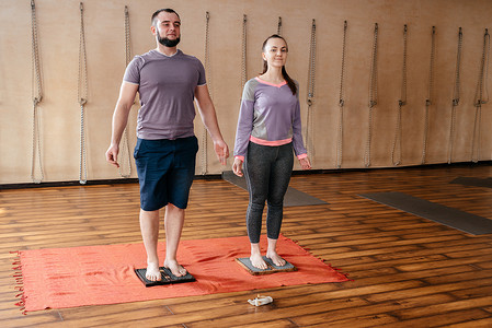 男教练教女人赤脚站在钉子床上，站在萨杜瑜伽板上