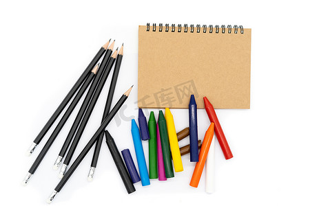 黑色双12摄影照片_图片上方一个棕色封面的笔记本，12支彩笔