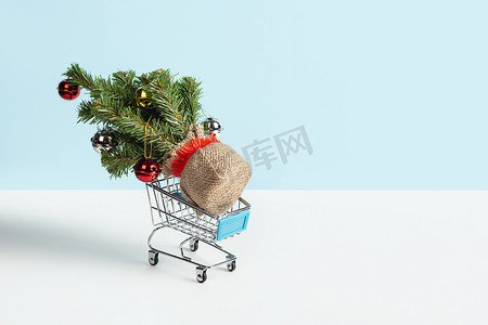 圣诞树放在蓝色购物车里，来自一家超市，隔离在浅蓝色的免费环境中。