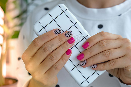 修剪整齐的女性手与时尚的粉红色指甲拿着手机。