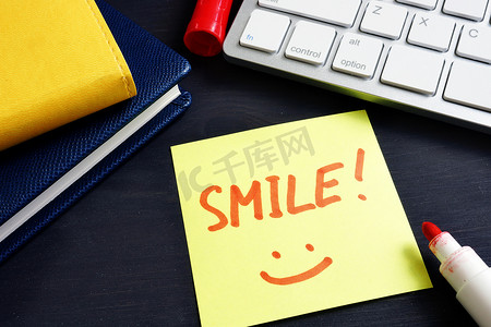 手写引文摄影照片_带有标志微笑的备忘录贴在办公室里。