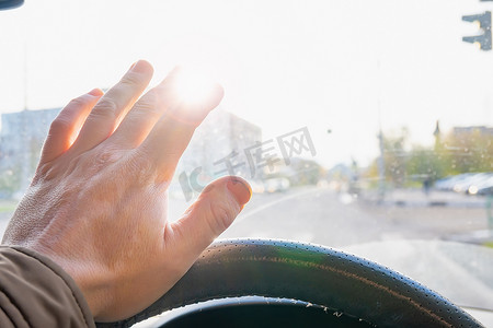 司机握着方向盘的手遮住了刺眼的阳光