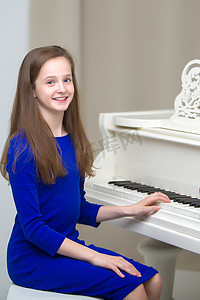一个十几岁的女孩正在一架白色三角钢琴上弹奏。
