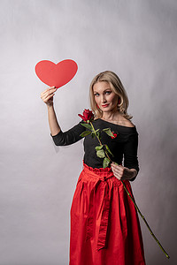 一个女孩手里拿着一朵玫瑰和一颗心，一个调情板，在地板上举行一场美丽的婚礼。