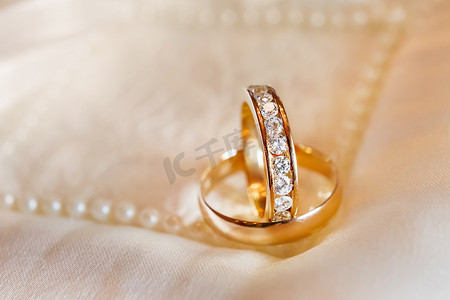 丝绸织物上镶有钻石的金色结婚戒指。