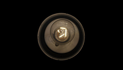 纯黑色灯容器中的传统复古透明单灯泡