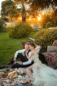 日落时分，新婚夫妇在草坪上共进晚餐。法国日落时分，一对夫妇坐着喝茶