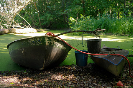 老独木舟和一艘木船靠在池塘上，上面有桶